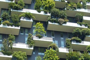 Eine Hausfassade mit vielen Balkons. Auf allen Balkons sind Bäume angepflanzt.